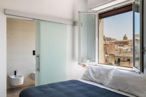 a bedroom with a bed and a window with a view at Mansarda Aurispa in Noto