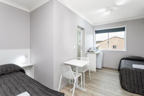 a bedroom with a bed and a desk and a table at Burleigh Gold Coast Motel in Gold Coast