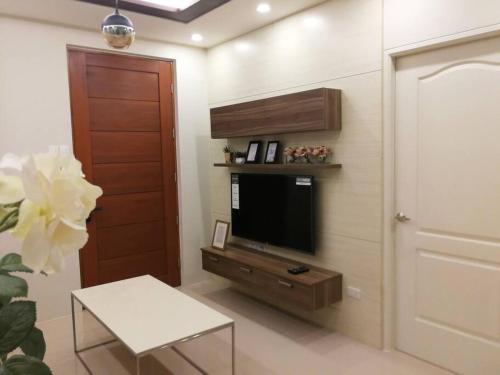 ein Wohnzimmer mit einem TV an der Wand in der Unterkunft Adria Residences - Emerald Garden - 2 Bedroom Unit for 4 person in Manila