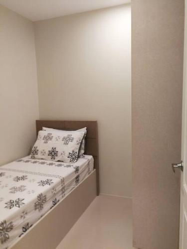 a small bed in a white room with a pillow at Adria Residences - Emerald Garden - 2 Bedroom Unit for 4 person in Manila