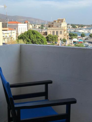 a blue chair on a balcony with a view of a city at Hotel Areti in Aegina Town