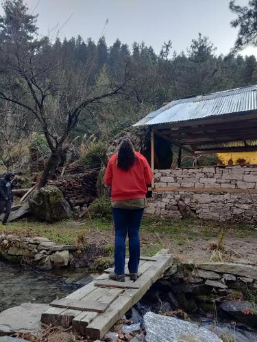 a woman standing on a bridge over a stream at Ikigai Manali in Nagar