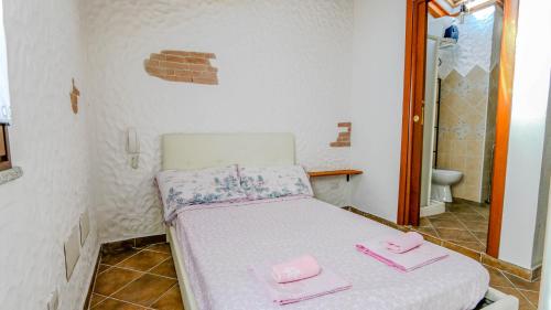 a small room with a bed with pink towels on it at Welcomely - Sa Dommedda in Nuoro