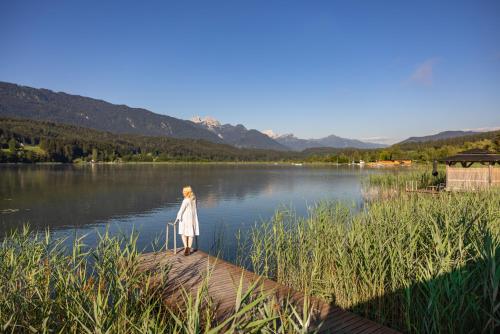 a woman standing on a dock near a lake at Lake Resort Pressegger See in Hermagor