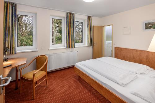 Schlafzimmer mit einem Bett, einem Schreibtisch und Fenstern in der Unterkunft Academy Lodge Boardinghouse in Hamburg