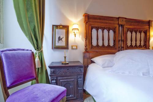 a bedroom with a wooden bed and a purple chair at B&B Il Marchese Del Grillo in Sulmona
