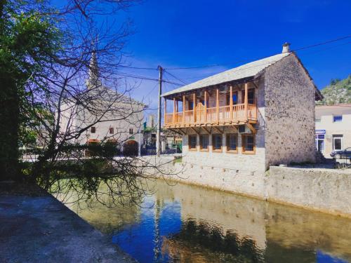 a building with a deck on the side of a river at National Monument Konak in Stolac