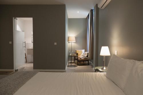 a bedroom with a bed and a living room with a chair at Hygge House in Lisbon