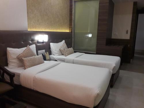 a hotel room with two beds and a mirror at Hotel Ramaya in Gwalior