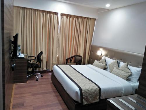 a hotel room with a large bed and a desk at Hotel Ramaya in Gwalior