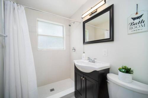 a white bathroom with a sink and a mirror at Fully Renovated house 10 min to Mayo Clinic in Jacksonville
