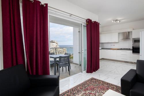 uma sala de estar com cortinas vermelhas e uma mesa com cadeiras em Sea View Apartment 2 bedrooms 2 bathrooms, 2 minutes away from the sea em St Julian's