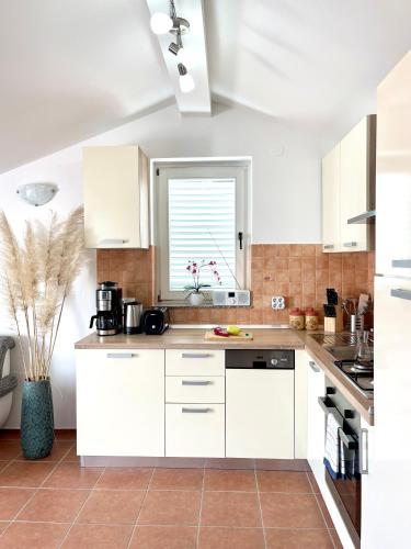 a kitchen with white cabinets and a window at Apartment Lady Daniela mit Meerblick in Lovran in Lovran