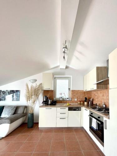 a kitchen with white cabinets and a brown tile floor at Apartment Lady Daniela mit Meerblick in Lovran in Lovran