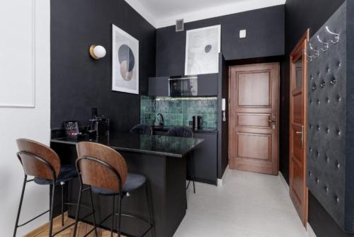 a kitchen with black walls and a bar with stools at Angel apartmens in Wrocław