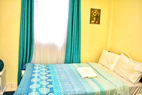 a bedroom with a bed with blue curtains and a window at Classic Studio Milimani - Wi-Fi and Parking in Kisumu