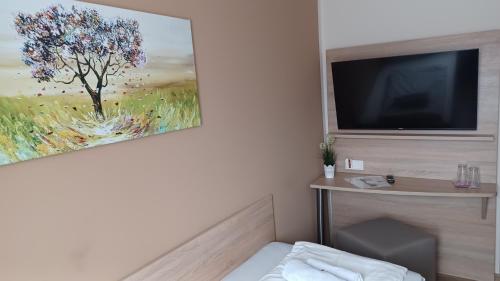a room with a television and a painting on the wall at Pension am Stern in Leipzig
