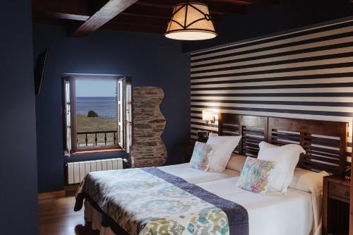 a bedroom with a large bed and a window at Hotel Pleamar in Puerto de Vega