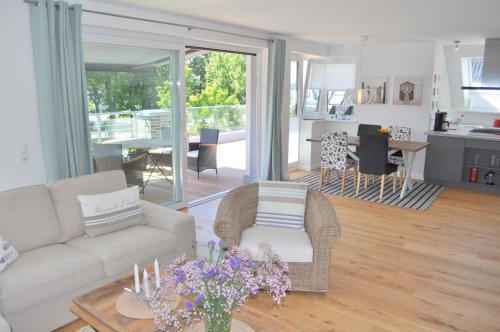 Una sala de estar con un sofá y una mesa con flores. en Maison du Port, en Timmendorfer Strand