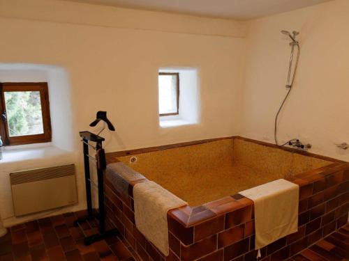 une grande baignoire en briques dans une pièce avec une fenêtre dans l'établissement Charming House in Ardèche near Les Vans, à Saint-Genest-de-Bauzon