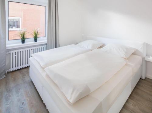 uma cama branca num quarto com uma janela em weitSicht em Norderney