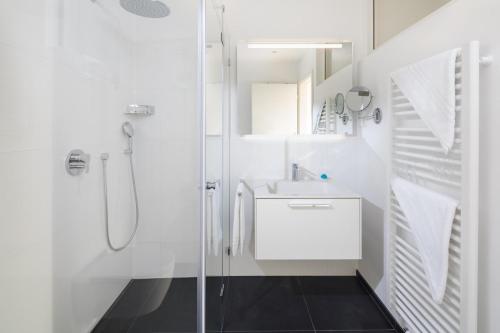 een witte badkamer met een wastafel en een douche bij Seebär Norderney in Norderney