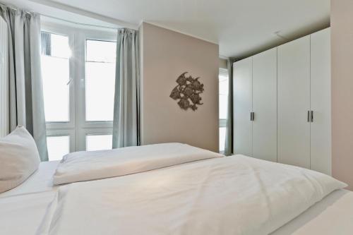 ein weißes Bett in einem Schlafzimmer mit einem Fenster in der Unterkunft Sonne 3 in Norderney