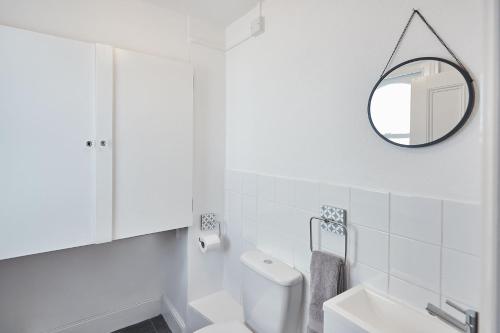 La salle de bains blanche est pourvue de toilettes et d'un miroir. dans l'établissement Beautiful Sea View Apartment in St Leonards on Sea, à St. Leonards