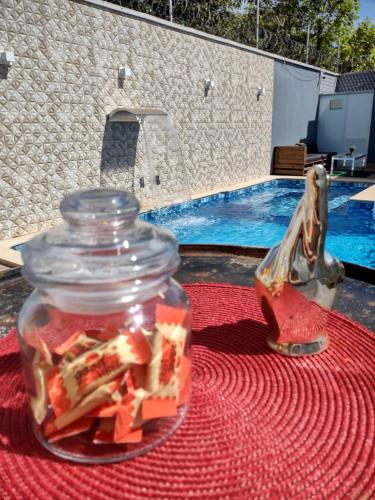 a jar of food sitting on a table next to a pool at Casa com Piscina e 3 Quartos Climatizados 8km do Centro in Palmas