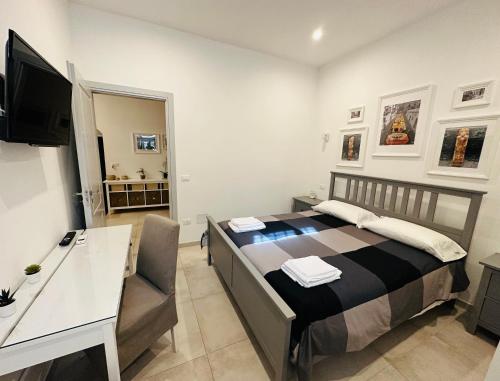 a bedroom with a bed and a desk and a television at Tannur Del Carmine in Noto
