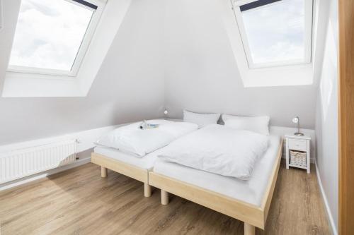 1 dormitorio blanco con 2 camas y 2 ventanas en Windrose 19 en Norderney