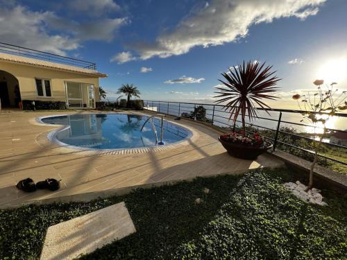 a swimming pool with a view of the ocean at Luxury villa with private heated pool, garden and views of the sea and mountains. in Arco da Calheta