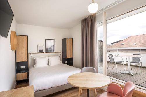 um quarto de hotel com uma cama e uma varanda em Apparthotel Privilodges Le Royal em Annecy