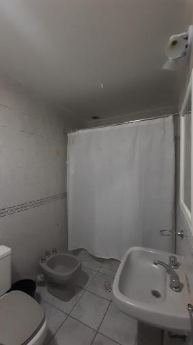 a white bathroom with a toilet and a sink at DEPARTAMENTO LAPRIDA in La Banda