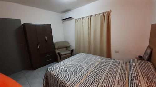 een slaapkamer met een bed, een dressoir en een stoel bij DEPARTAMENTO LAPRIDA in La Banda