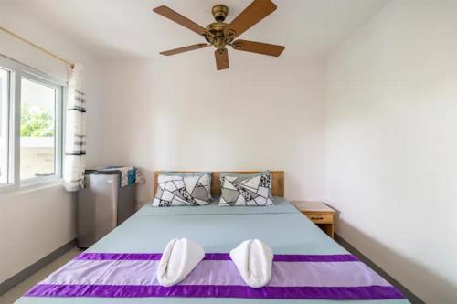Un dormitorio con una cama con ventilador de techo. en Beyond Island, en Moalboal