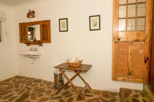 a bathroom with a wooden table and a sink at Wild Olive Cottage in Graaff-Reinet