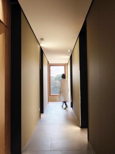 a woman walking down a hallway with a window at Qgat Restaurant Events & Hotel in Sant Cugat del Vallès