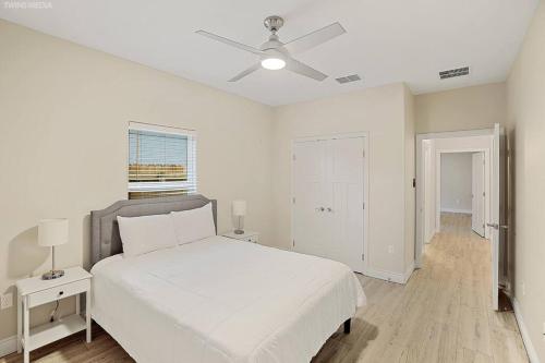 1 dormitorio blanco con 1 cama y ventilador de techo en Luxurious Coastal Retreat Brand New 4BR Home with Fast WiFi, 15 min to Beach!, en Corpus Christi
