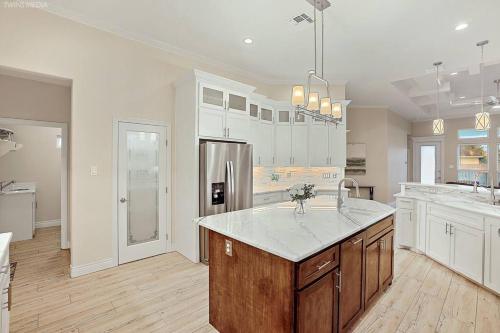 a large kitchen with white cabinets and a refrigerator at Luxurious Coastal Retreat Brand New 4BR Home with Fast WiFi, 15 min to Beach! in Corpus Christi