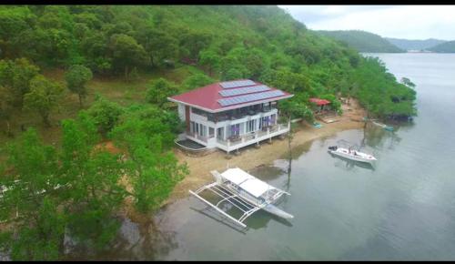a large house on the water with a boat at NaturesWay/TRAVELCORON in Coron