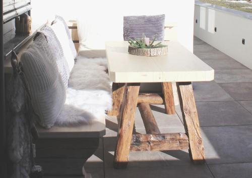 a table and a bench with pillows on a porch at Apartment VIERSTERNE in Neustift im Stubaital