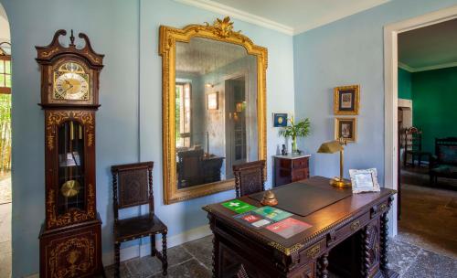 een kamer met een bureau, een spiegel en een staande klok bij Palácio de Sintra Boutique House in Sintra