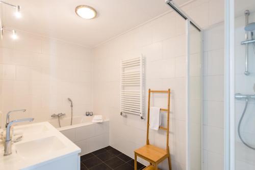 a white bathroom with a sink and a shower at Staetige Dames in Nes