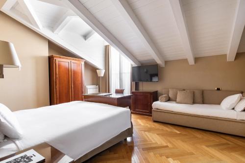 een slaapkamer met een wit bed en een bank bij Hotel Continentale in Trieste