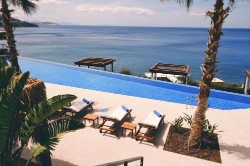 a pool with chairs and a view of the ocean at Allium Bodrum Resort & Spa in Yalıkavak
