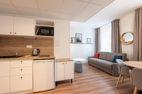 a kitchen and living room with a couch and a table at Apparthotel Privilodges Le Royal in Annecy