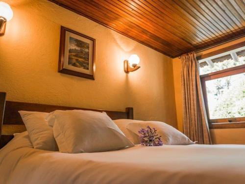 a bedroom with a bed with white pillows and a window at Fazenda Hotel Itapuá in Monte Verde