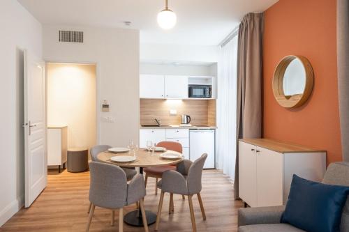 a kitchen and a dining room with a table and chairs at Apparthotel Privilodges Le Royal in Annecy