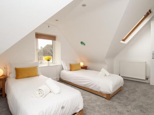 two beds in a attic room with a window at Nine Barrow View in Swanage